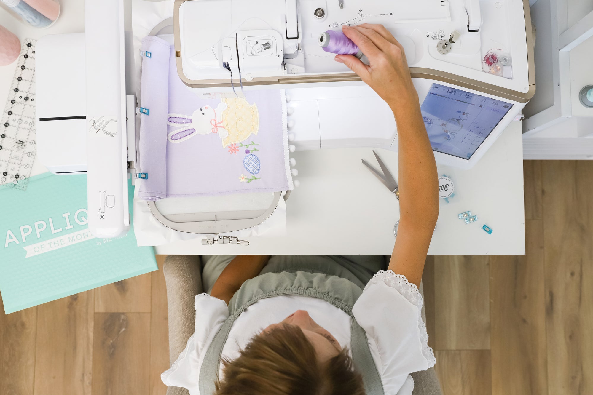 Person using a sewing machine with various materials and tools on a table.
