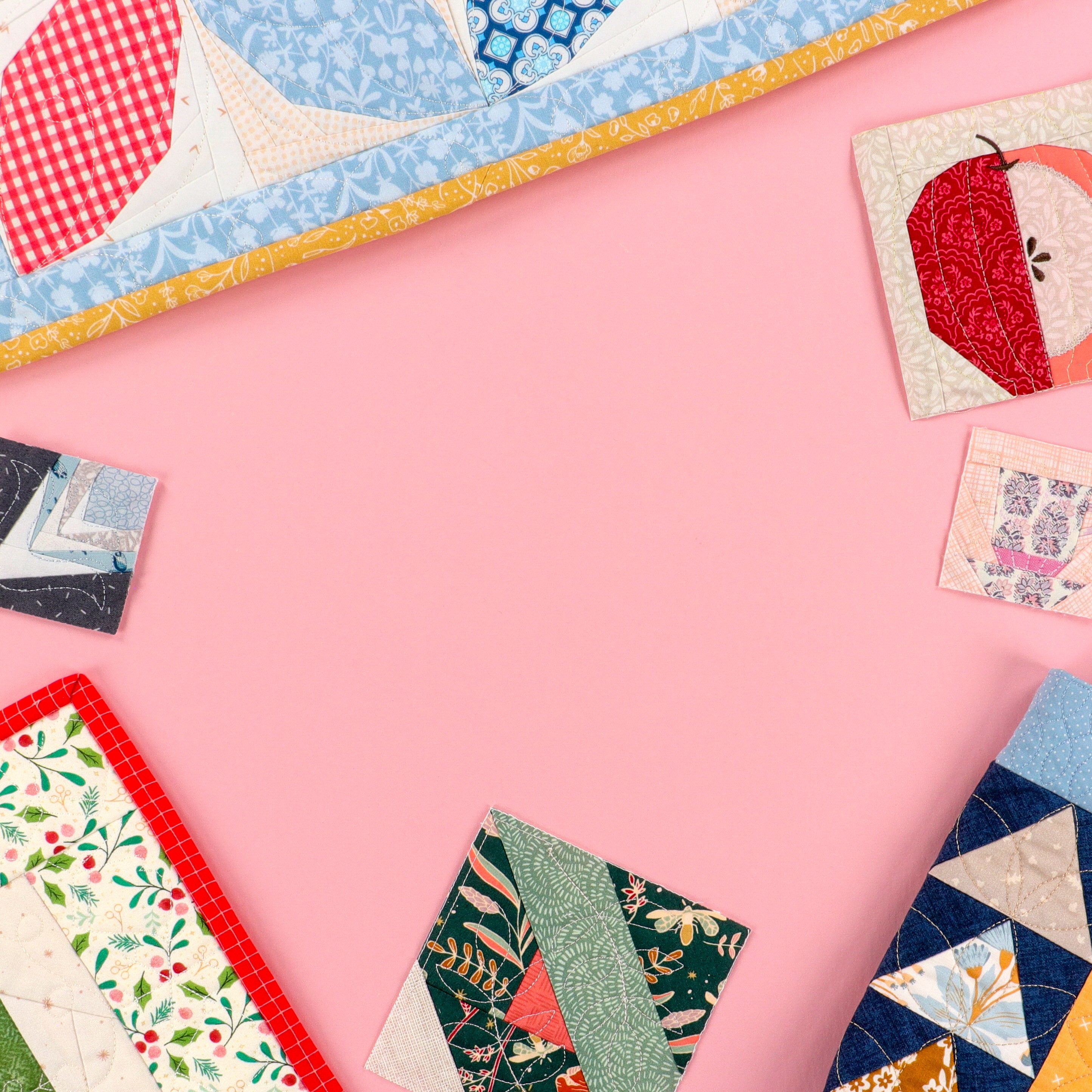 Colorful quilted fabric squares on a pink background