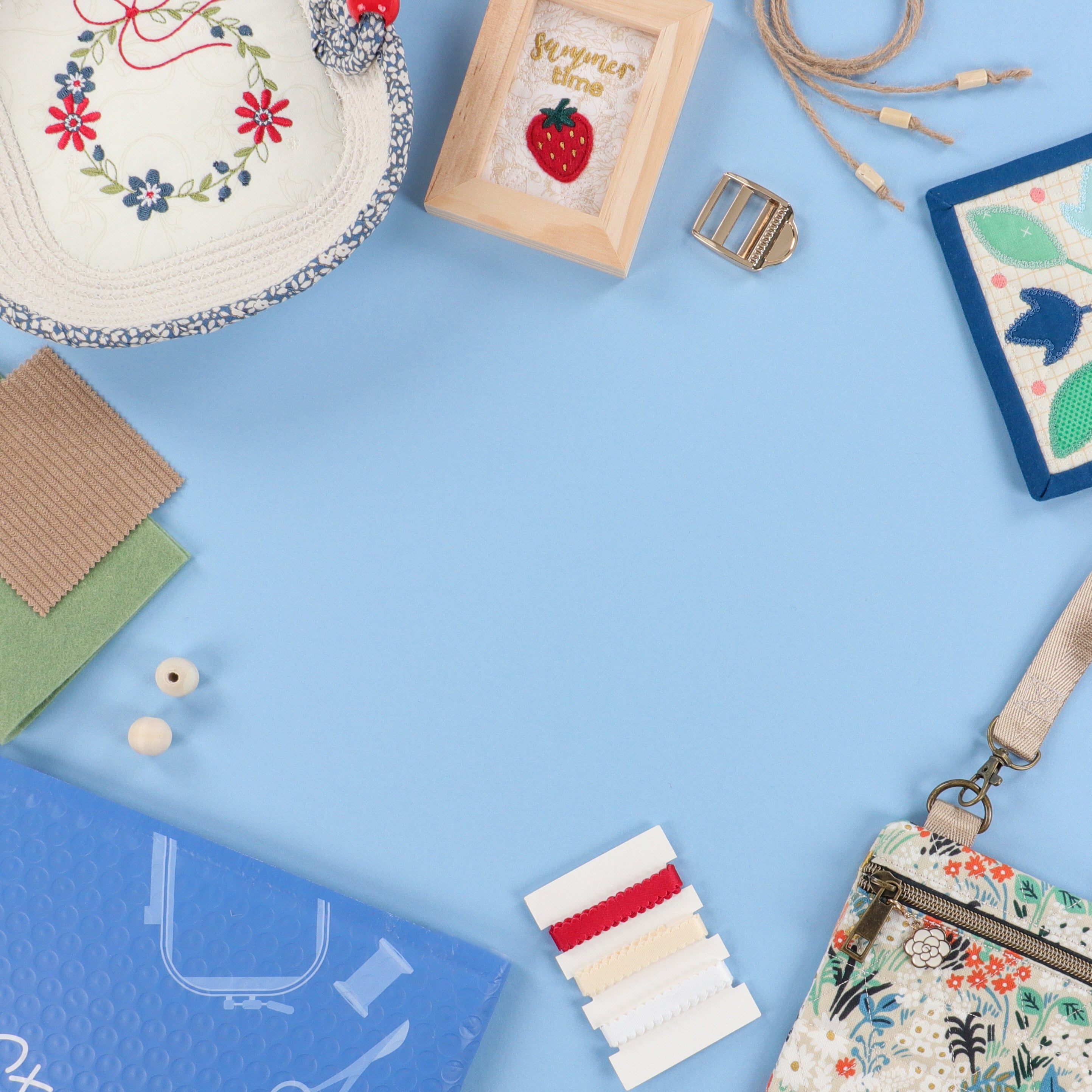 Collection of machine embroidery including fabric, thread, and a floral bag on a blue background