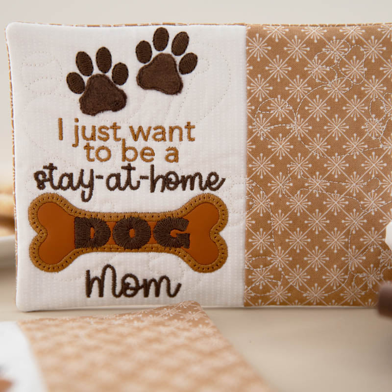 Mug rug with paw prints, text 'I just want to be a stay-at-home dog mom', and a bone shape on a beige background.