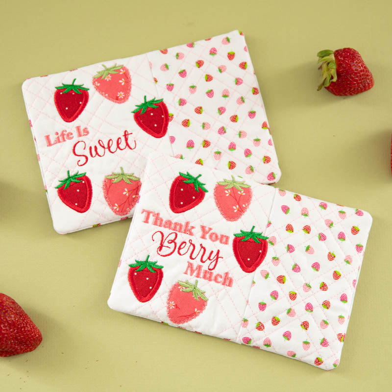 Two quilted mug rugs with strawberry pattern, alongside "Life Is Sweet" and "Thank You Berry Much" embroidered text. 