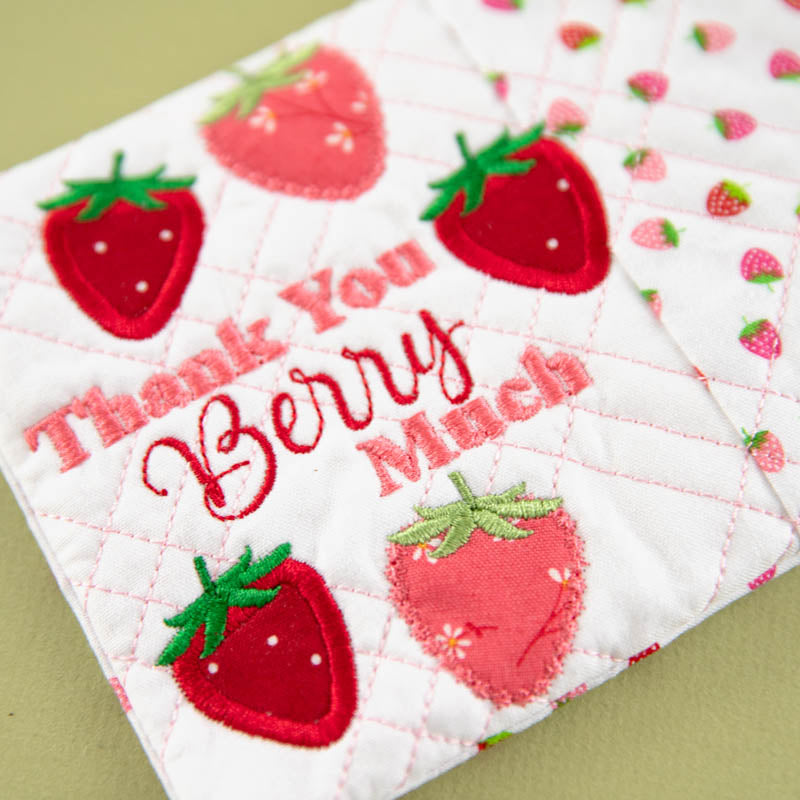 Quilted mug rug with strawberry pattern and 'Thank you, Berry Much' text on a green background