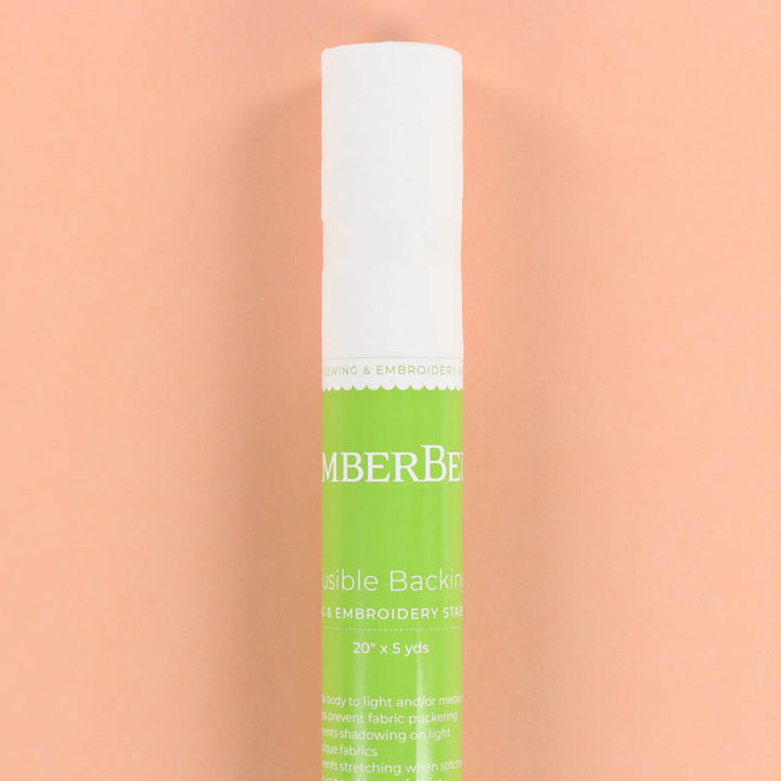 Roll of embroidery stabilizer with a white and green label on a peach background