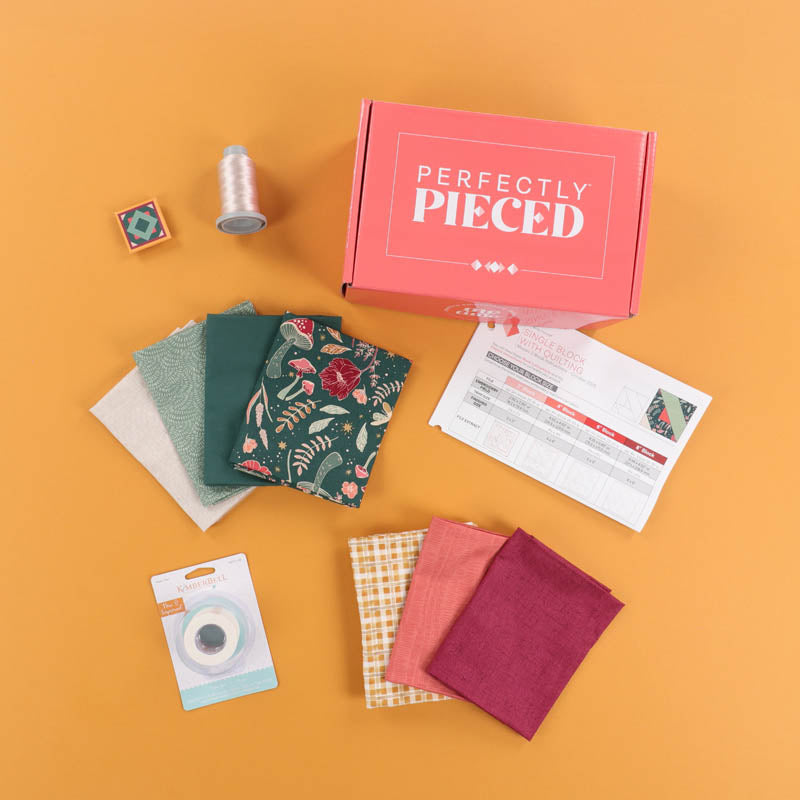 October 2025 Perfectly Pieced box with contents spread out across a light orange background, fabric, fabric tape, and thread.