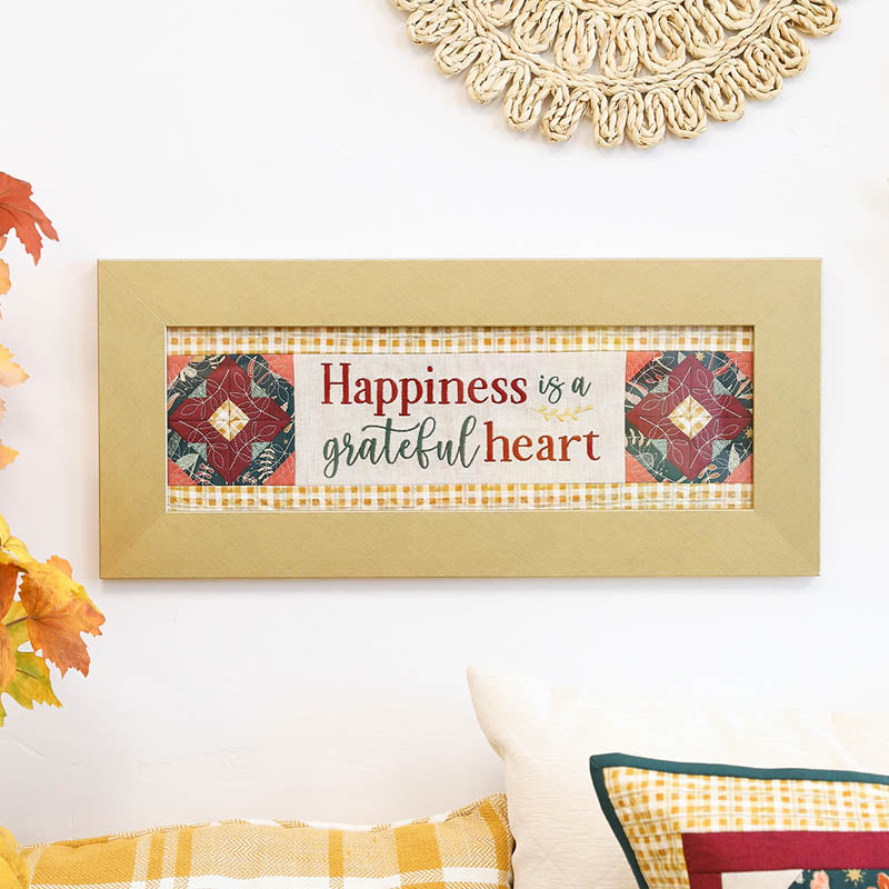 Decorative wall art with 'Happiness is a grateful heart' text on a checkered background.