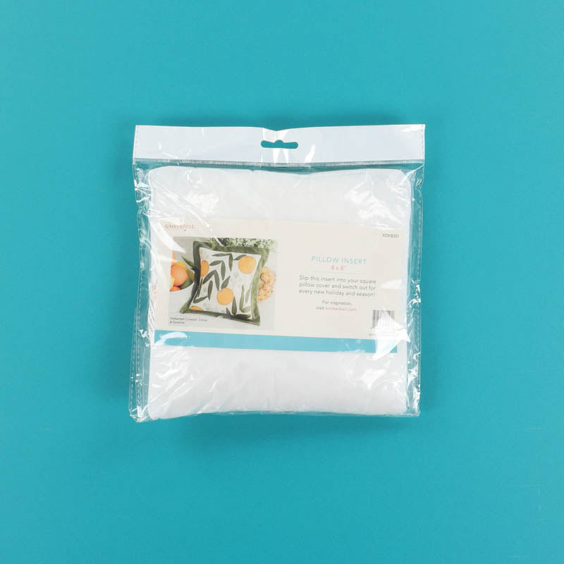 Packaged white pillow insert on a teal background