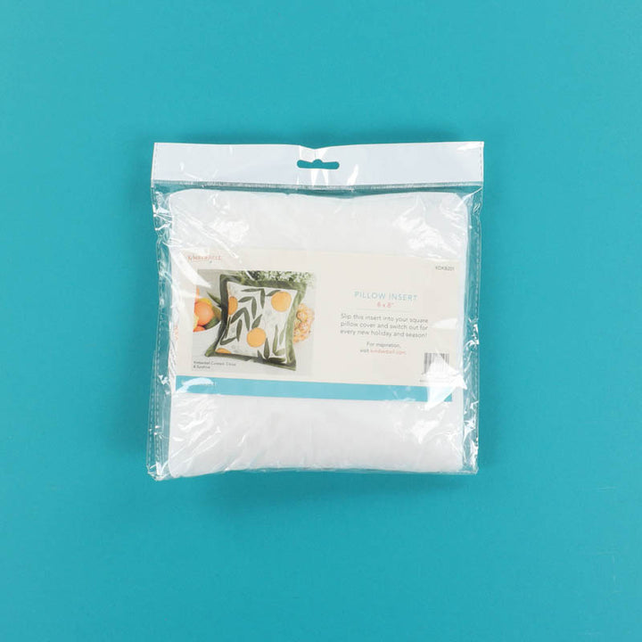 Packaged white pillow insert on a teal background