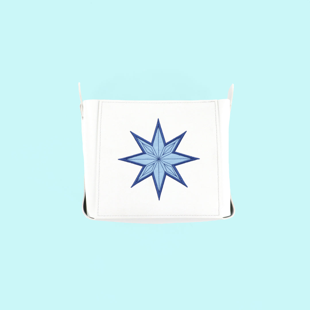 White pouch with a blue snowflake applique design on a light blue background