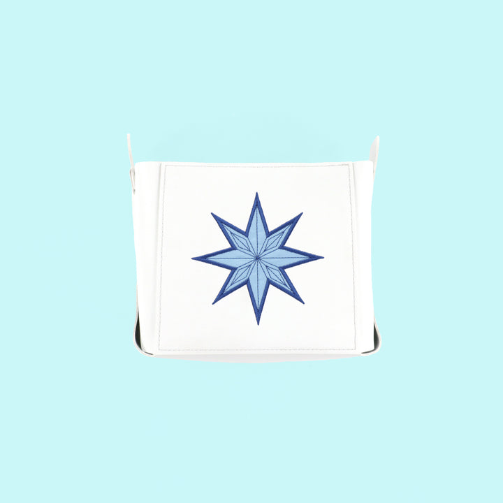 White pouch with a blue snowflake applique design on a light blue background