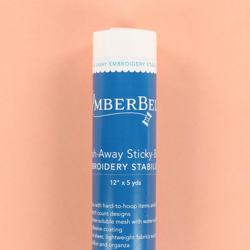 Blue roll of Kimberbell Wash-Away Sticky-Back Embroidery Stabilizer on a peach background