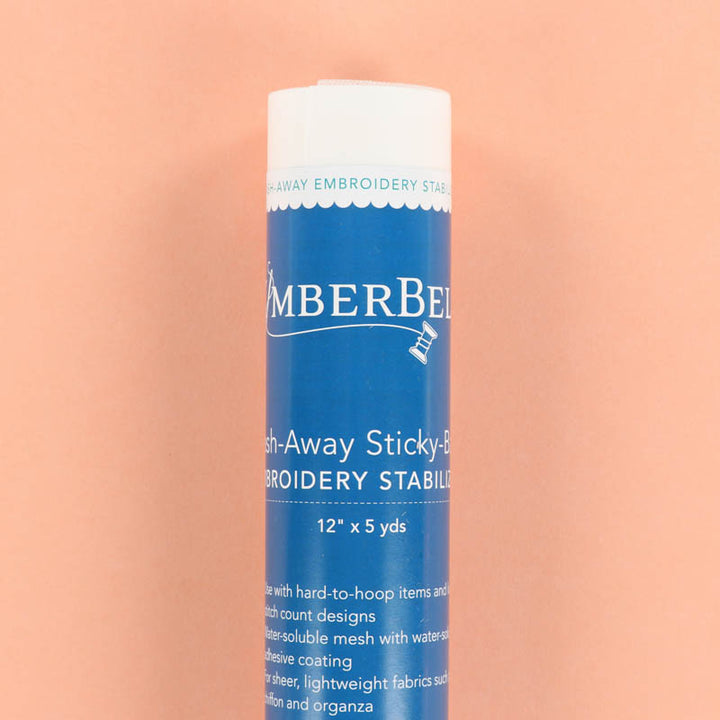 Blue roll of Kimberbell Wash-Away Sticky-Back Embroidery Stabilizer on a peach background