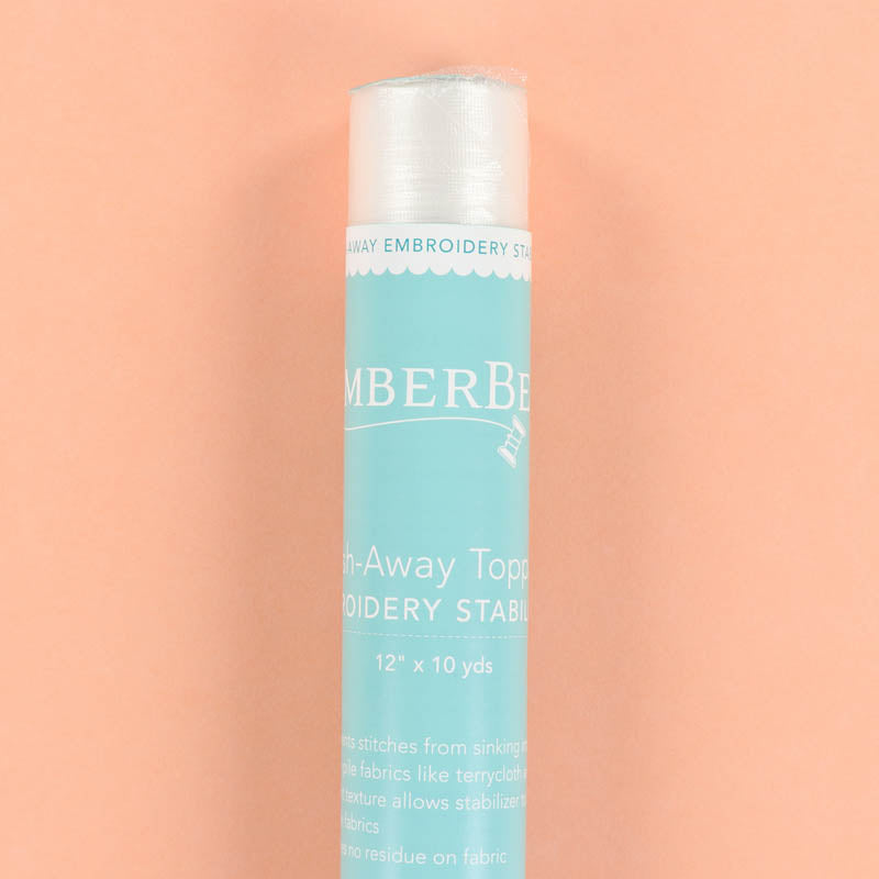 Blue and white roll of wash-away topping stabilizer on a peach background