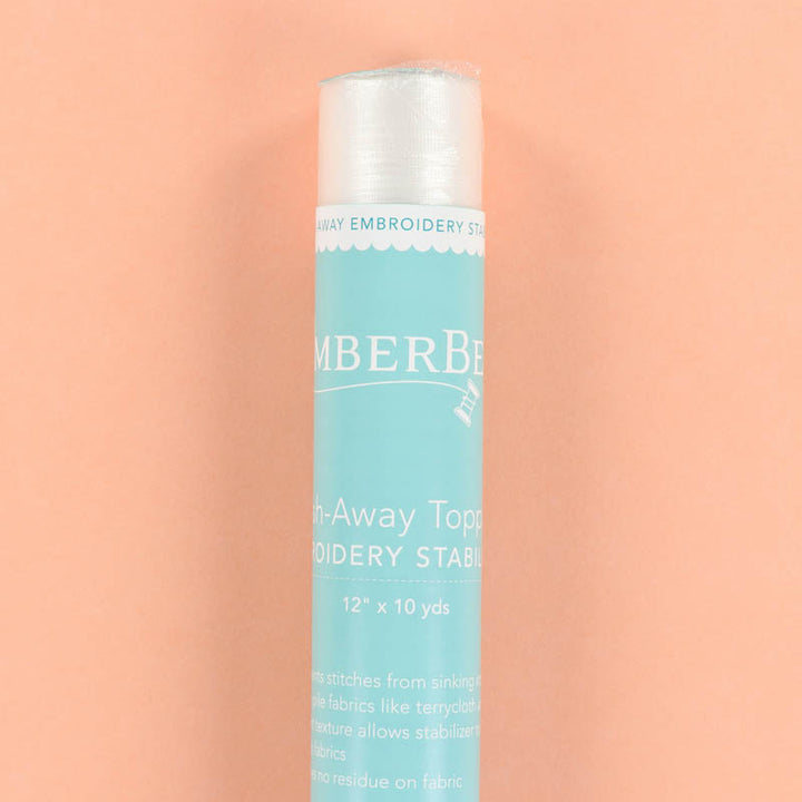 Blue and white roll of wash-away topping stabilizer on a peach background