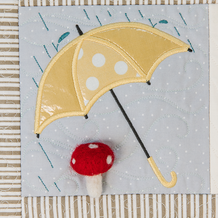 Quilt block with a yellow polka dot umbrella and red mushroom on a gray background