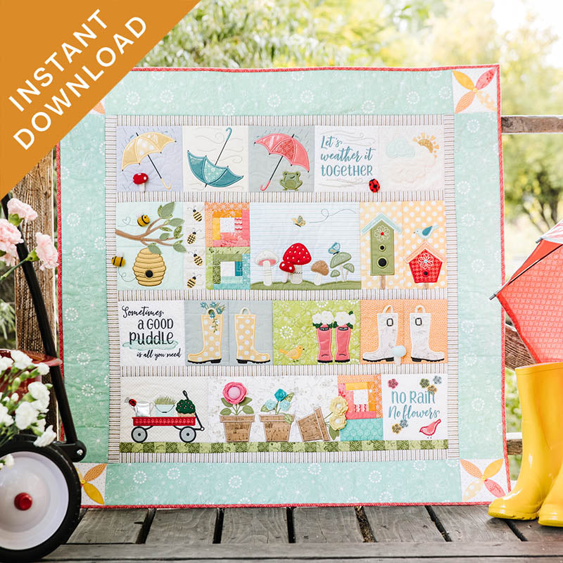 Colorful quilt with various patterns and elements on a wooden surface with flowers and rain boots.