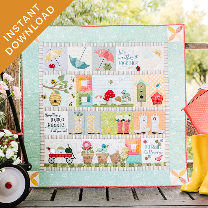 Colorful quilt with various patterns and elements on a wooden surface with flowers and rain boots.